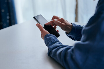 部屋でスマホを操作するシニア女性