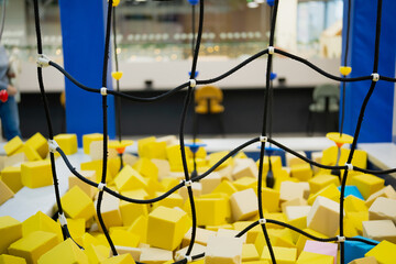 Indoor children play area with safety net in foreground and foam cubes pit behind showing modern recreational space designed for active play