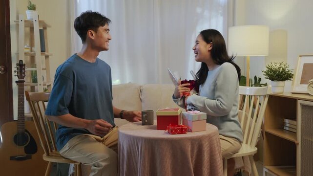 Love fills room as happy young couple celebrates valentine day, romantic kiss on face showing sweet affection, lovers enjoy intimate home celebration with gifts and smiling faces.