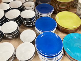 Stacks of colorful plates are sold in a kitchenware store.