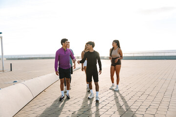 Two male athletes walk and laugh while talking and behind them is a group of three athletes
