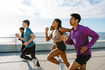 A group of five athletes look ahead and run until three of them are side by side
