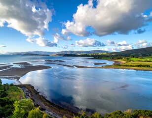 Expansive coastal landscape showcasing a wide river delta meeting the sea. Lush green fields border the shoreline with dramatic cloud formations above