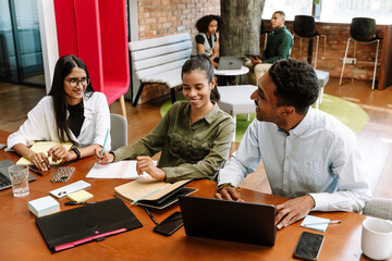 Group of three workers laughing and talking while sitting at a table