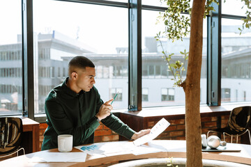Male worker holding a pencil and reading a document while sitting at a desk