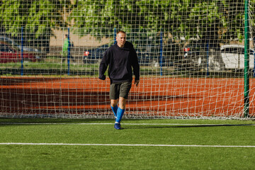 The goalkeeper walks in front of the goal and looks ahead