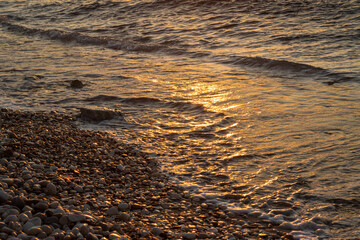 Pebbles and sea detail in the sunset, Greece