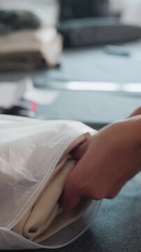 fast hands sealing folded apparel inside clear pouch on fulfillment table packer smooths and compresses garments into zip pouch, checks labels and sealing integrity for online orders, efficient