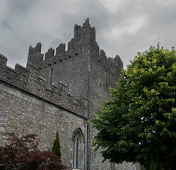 The Trinitarian Abbey in Adare, Ireland, with a crenellated parapet and arched window an overcast sky