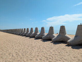 Heavy concrete tetrapods lie on a bright sandy shore.