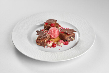 three squares of rich, nutty chocolate brownie are arranged around a central scoop of vibrant pink sorbet or ice cream