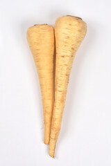 Two whole raw parsnips, long and tapered with light beige skin, are positioned vertically and slightly overlapping on a plain white background