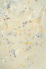 A vertical, close-up view captures the texture of a white, creamy meringue batter mixed with dark chocolate pieces, orange zest, and chopped nuts