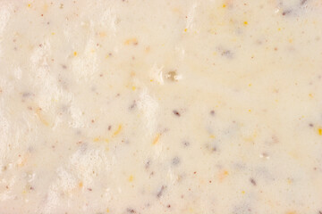 A horizontal, close-up view captures the texture of a white, creamy meringue batter mixed with dark chocolate pieces, orange zest, and chopped nuts
