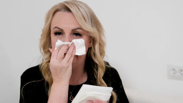 Sneezing tissue woman caucasian woman sneezing and blowing nose into tissue at home