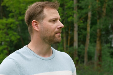 Handsome young man standing outdoors. Male thinking looking around feel happy, calm and serious....