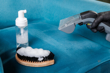 Professional upholstery cleaning with extraction vacuum and detergent on blue armchair