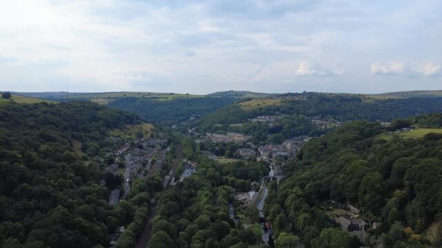 Aerial view of Hebden Bridge showing the town surrounded by trees with the canal and railway line along the Calder valley