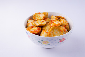 A bowl of spicy Indonesian jengkol (dogfruit) cooked in balado sauce, arranged with a small potted flower and wooden utensils. A popular traditional dish with a unique aroma