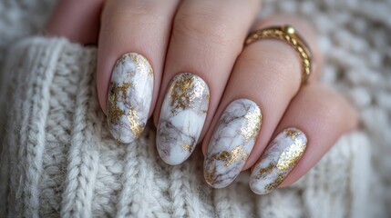 Luxury marble nail art with gold foil detail on almond shaped nails in cozy winter style