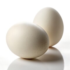 Two large white eggs rest on a reflective surface against a bright white background in a studio setting