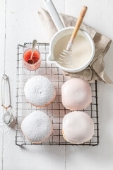 Tasty and hot donuts with white icing on cooling grate