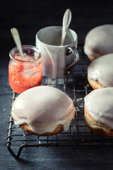 Tasty donuts with red jam on cooling grate