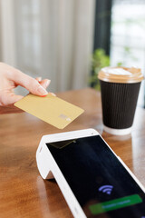 Vertical close up of contactless NFC card tap on POS terminal at cafe table