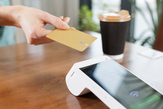 Contactless NFC card payment at cafe table with POS terminal close up