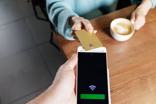Overhead smartphone POS contactless NFC card payment at cafe table