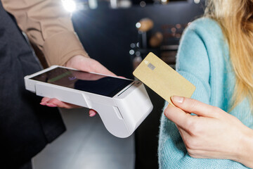 Customer contactless NFC card payment with handheld POS terminal in bar interior