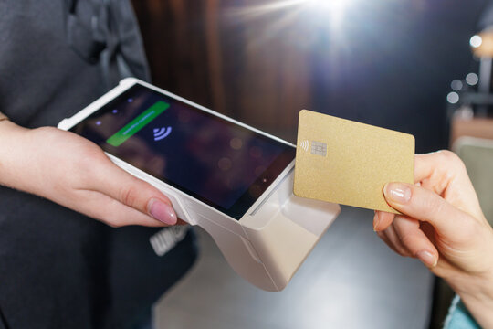 Close up NFC contactless card transaction with portable POS terminal in restaurant