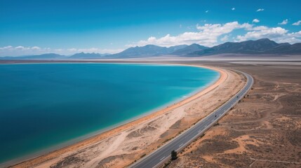 A scenic coastal drive along a vibrant turquoise lake in an arid landscape with distant mountains
