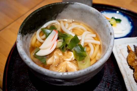 Hot Japanese Udon Noodle Soup in Ceramic Bowl Served with Green Onions and Kamaboko Fish Cake