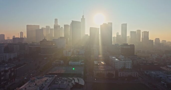 Stunning aerial silhouette shot at Sunrise over Downtown Los Angeles emerge from fog with golden morning light