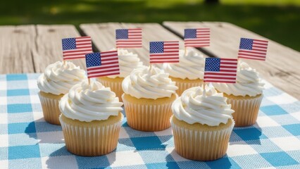Patriotic cupcakes with American flags for a 4th of July celebration. Festive vanilla desserts on a picnic table outdoors for a summer holiday party