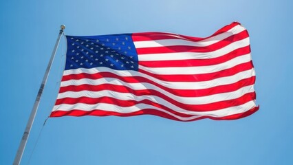 Obraz premium American flag waving against bright blue sky, showcasing vibrant red, white, and blue colors. Iconic American flag displays stars and stripes, symbolizing national unity and liberty for country.