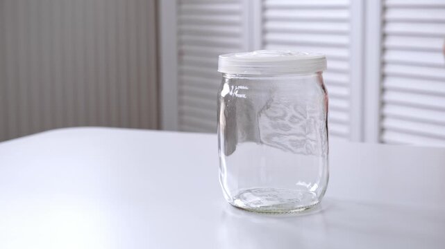 A man puts on a nylon lid onto an empty glass jar. Air conservation. The concept of nonsense. Reusable tableware for storage. Environmentally friendly material. High quality 4K footage.