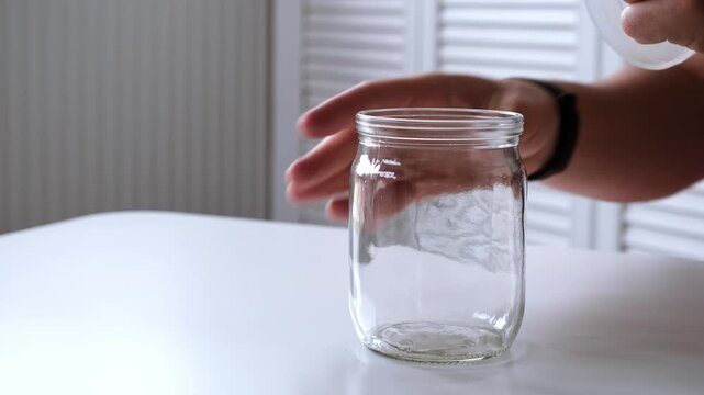 A man removes a nylon lid from an empty glass jar. Air conservation. The concept of nonsense. Reusable tableware for storage. Environmentally friendly material. High quality 4K footage.