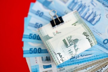 United Arab Emirates dirham money bills in big amount close up on red. Finance and banking concept