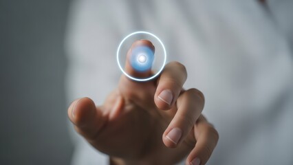 A close-up, slightly desaturated photograph depicts a human hand with a fair complexion, gently extending the index finger towards a glowing, circular blue holographic interface projected directly