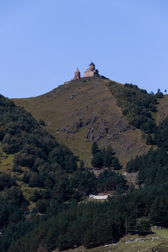 Distant view of Gergeti Trinity Church (Tsminda Sameba) on a Mountain Ridge near Stepantsminda, Caucasus Mountains, Georgia