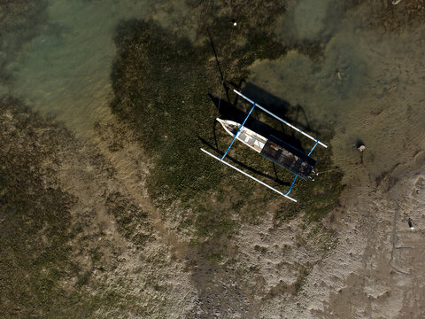 Aerial view of a Traditional Balinese Outrigger Boat (juking) in the sea at low tide, Bali, Indonesia