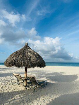 Two sun loungers and a straw parasol on a sandy beach, Eagle Beach, Aruba
