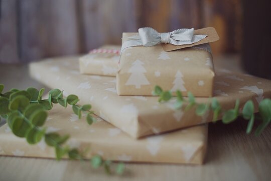 Close-up of a stack of Gift boxes wrapped in Christmas wrapping paper on a wooden table