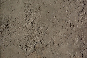 Uneven brown-gray plaster wall with natural imperfections. Minimalist texture for design, architecture, or abstract use.  