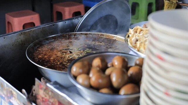 The video background shows Tawan cooking over a charcoal stove, the aroma enticing and delicious, the kind of noodle soup or kway chap commonly sold in tourist areas.