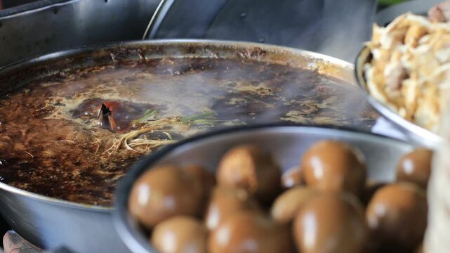 The video background shows Tawan cooking over a charcoal stove, the aroma enticing and delicious, the kind of noodle soup or kway chap commonly sold in tourist areas.