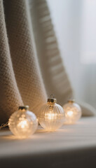 Decorative glass Christmas ornaments glowing on a soft white blanket  