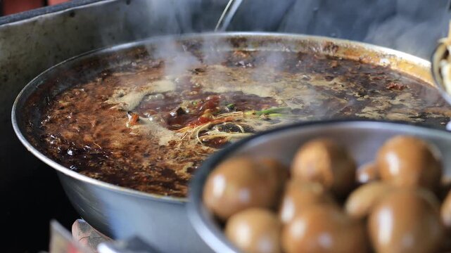 The video background shows Tawan cooking over a charcoal stove, the aroma enticing and delicious, the kind of noodle soup or kway chap commonly sold in tourist areas.